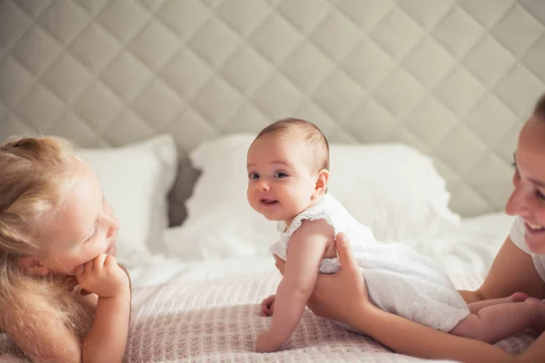 Joven hermosa madre sostiene a un bebé. La hermanita besa a su hermanita. Nena. Dormitorio para niños . — Foto de Stock