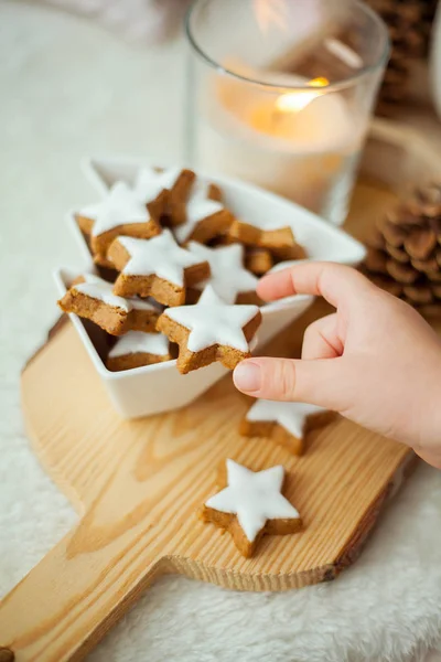 Christmas cookies stars, cocoa on a wooden board. Christmas decor, candles, plaid. Childrens hand holds cookies.