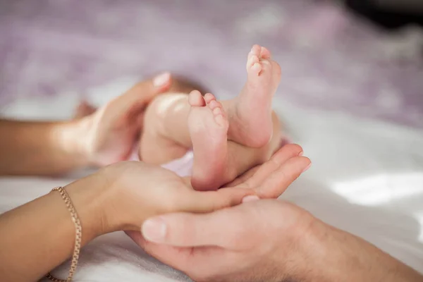 Mamá y papá sostienen las piernas del bebé. Primer plano . — Foto de Stock