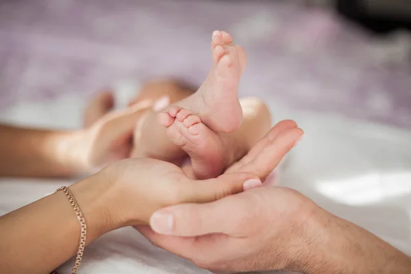 Mamá y papá sostienen las piernas del bebé. Primer plano . — Foto de Stock