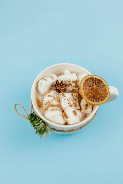 코코아와 마시멜로가 들어 있는 커다란 흰색 머그와 푸른 배경에 있는 계피입니다. 크리스마스 동기. 전통적 인 겨울 음료. — 스톡 사진