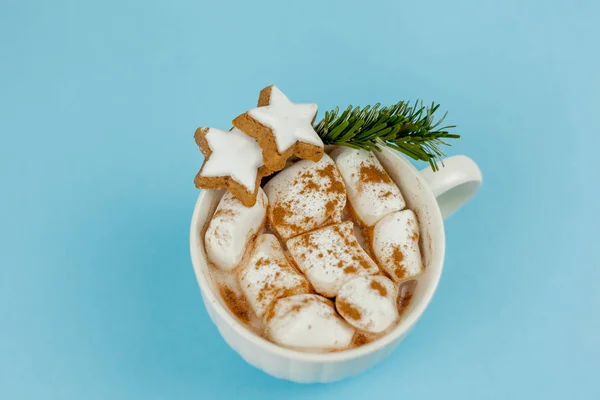 Ein großer weißer Becher mit Kakao und Marshmallows, Zimt auf blauem Hintergrund. Weihnachtsplätzchen. traditionelles Wintergetränk. — Stockfoto