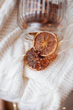 Hasır sepet, örgü süveter, kurutulmuş turunçgillerle dolu güzel bir cam kavanoz, Noel ışıkları. Samimi.