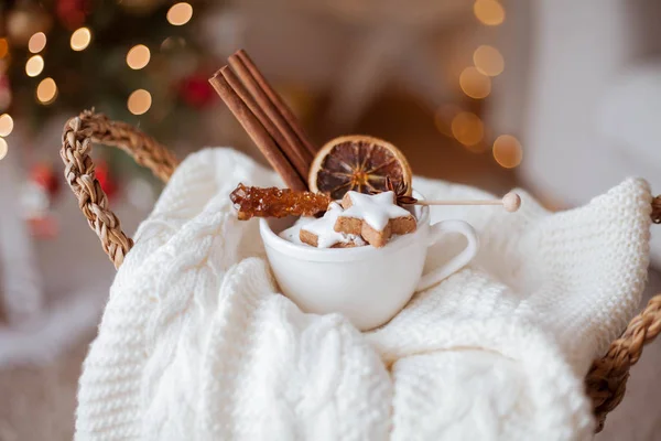 Rieten mandje, gebreide trui, gedroogde citrusvruchten, kaneelstokjes, kerstkoekjes, kerstverlichting. Gezellig. — Stockfoto