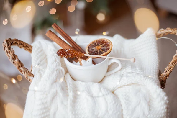 Cesta de vime, suéter de malha, citrinos secos, paus de canela, biscoitos de Natal, luzes de Natal. Aconchegante . — Fotografia de Stock