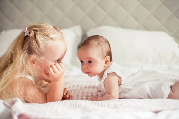 Genç ve güzel bir anne bir bebek doğuruyor. Küçük kız kardeşi küçük kız kardeşini öper. Bebek. Çocuk yatak odası. — Stok fotoğraf