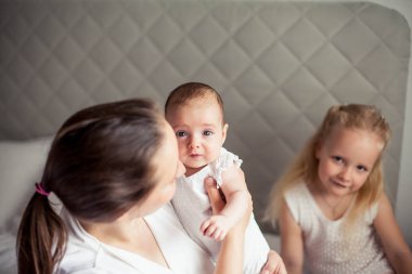 Genç ve güzel bir anne bir bebek doğuruyor. Küçük kız kardeşi küçük kız kardeşini öper. Bebek. Çocuk yatak odası.