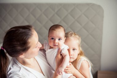 Genç ve güzel bir anne bir bebek doğuruyor. Küçük kız kardeşi küçük kız kardeşini öper. Bebek. Çocuk yatak odası.