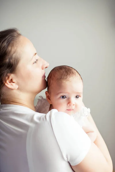 La giovane e bella madre tiene in braccio un bambino. Mamma bacia il suo bambino. Camera da letto per bambini . — Foto Stock