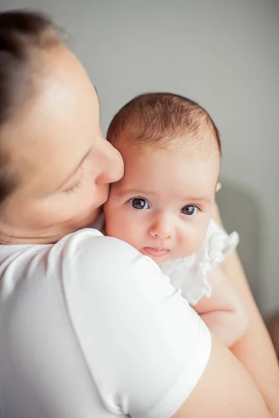 Młoda piękna matka trzyma dziecko. Mama całuje jej dziecko. Sypialnia dla dzieci. — Zdjęcie stockowe