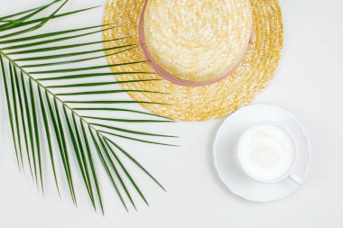 Tropical plant, womens straw hat, cappuccino mug on a white background. Womens things.