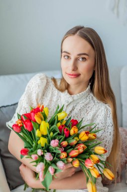 Güzel genç bir kadın elinde çok renkli bir lale buketi tutuyor. Bahar kadını portresi.