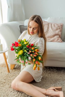 Güzel genç bir kadın elinde çok renkli bir lale buketi tutuyor. Bahar kadını portresi.