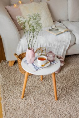 Evin içi bahar havası. Vazoda bir buket çiçek, bir fincan çay, sehpanın üstünde dekor. Ruh hali.