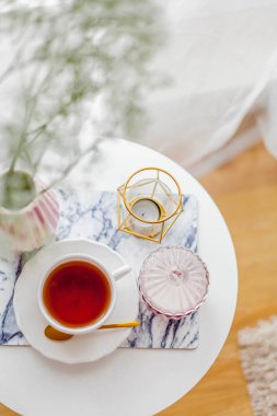 Evin içi bahar havası. Vazoda bir buket çiçek, bir fincan çay, sehpanın üstünde dekor. Ruh hali.