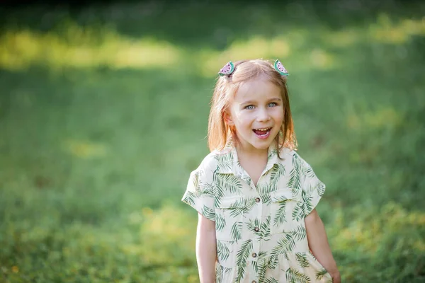 Little cute girl is sitting on the grass. Happy girl in the park. Summer. — Stock Photo, Image