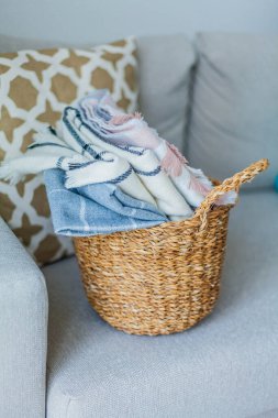 İçi örülmüş battaniyelerle dolu hasır bir rattan sepeti. Rahat ev aksesuarları. Bahar.