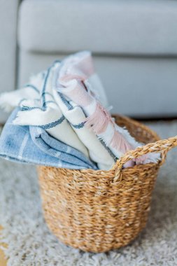 İçi örülmüş battaniyelerle dolu hasır bir rattan sepeti. Rahat ev aksesuarları. Bahar.