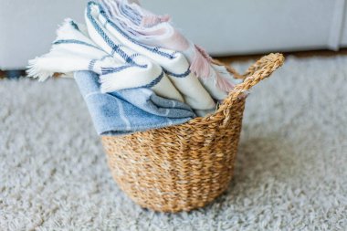 İçi örülmüş battaniyelerle dolu hasır bir rattan sepeti. Rahat ev aksesuarları. Bahar.