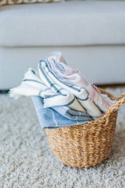İçi örülmüş battaniyelerle dolu hasır bir rattan sepeti. Rahat ev aksesuarları. Bahar.
