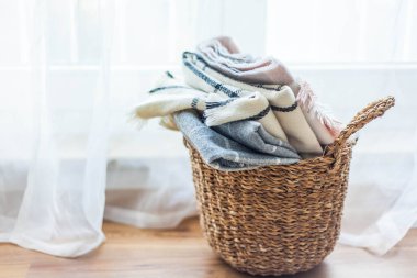 İçi örülmüş battaniyelerle dolu hasır bir rattan sepeti. Rahat ev aksesuarları. Bahar.