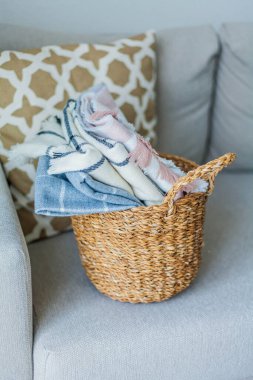 İçi örülmüş battaniyelerle dolu hasır bir rattan sepeti. Rahat ev aksesuarları. Bahar.