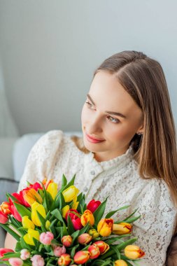 Güzel genç bir kadın elinde çok renkli bir lale buketi tutuyor. Bahar kadını portresi.