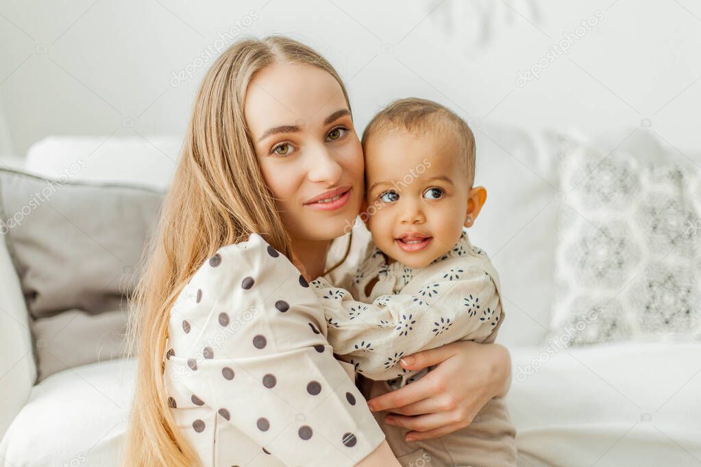 Happy mom and mulatto girl in home interior. Mothers Day. Baby.