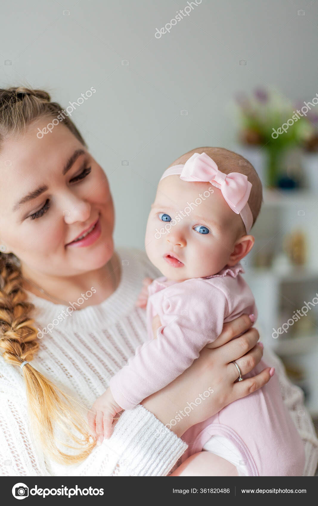 예쁜 한 젊은 엄마가 예쁜 파란 눈의 2 개월된 작은 딸을 품에 안고 있습니다. 신생아. — 스톡 사진 © Karelia89  #361820486, image size:1067x1700