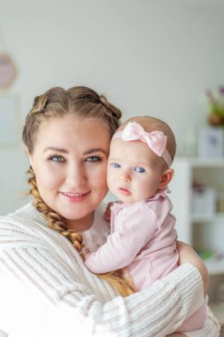 Güzel, genç bir anne, iki aylık küçük, mavi gözlü bir kızı kollarında tutuyor. Yeni doğan.