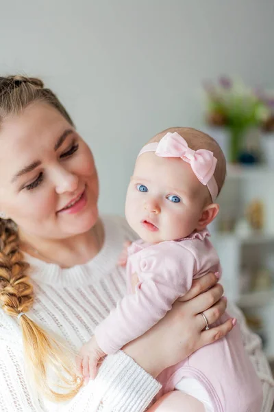 Una bella giovane madre tiene tra le braccia una piccola figlia di 2 mesi dagli occhi azzurri. Neonato . — Foto Stock