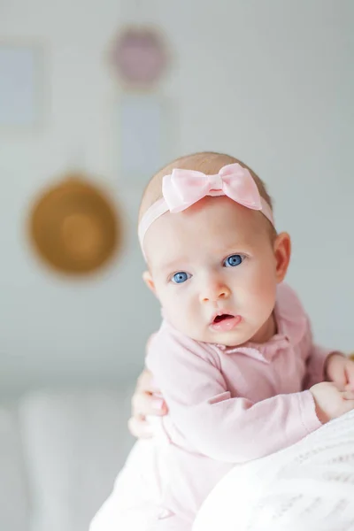A beautiful young mother holds in her arms a small pretty blue-eyed 2-month-old daughter. Newborn. — Stock Photo, Image