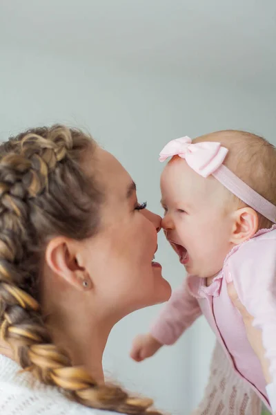 En vacker ung mor håller i sina armar en liten söt blåögd 2-månaders dotter. Nyfödd. — Stockfoto