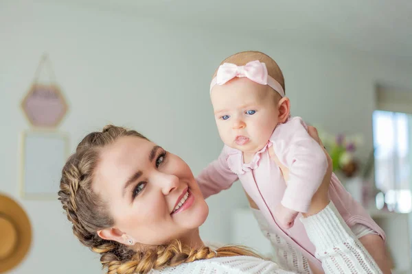 Una bella giovane madre tiene tra le braccia una piccola figlia di 2 mesi dagli occhi azzurri. Neonato . — Foto Stock