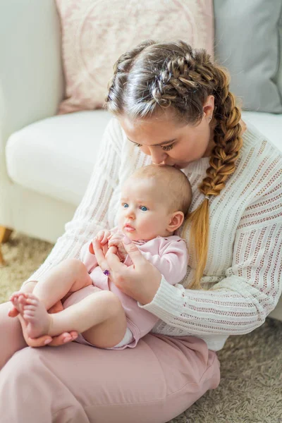 Una bella giovane madre tiene tra le braccia una piccola figlia di 2 mesi dagli occhi azzurri. Neonato . — Foto Stock