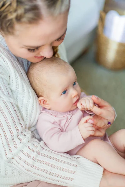Una hermosa madre joven sostiene en sus brazos a una pequeña hija de 2 meses de edad de ojos azules. Recién nacido . —  Fotos de Stock