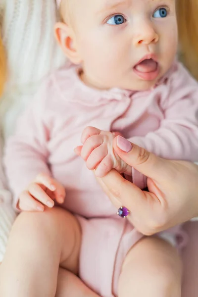 Primo piano. Bella giovane madre tiene per mano la sua figlioletta. Tesoro. Neonato . — Foto Stock
