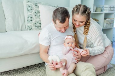 Güzel, genç ebeveynler yeni doğmuş kızlarını kollarında tutuyorlar. 2 aylık mavi gözlü küçük kız..