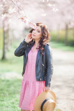 Çiçekli bir bahçede güzel genç bir kadın yürüyor. Koyu saçlı genç bir kadının portresi. Kiraz çiçekleri.