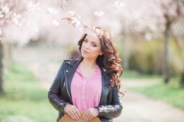 Çiçekli bir bahçede güzel genç bir kadın yürüyor. Koyu saçlı genç bir kadının portresi. Kiraz çiçekleri.