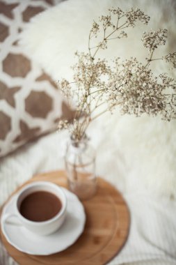 Bir fincan sıcak kakao, ahşap bir tezgah, yatağın üzerindeki cam vazoda kurumuş bir çiçek. Homellik.