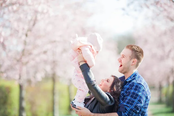 Genç Ebeveynler Kollarında Küçük Güzel Bir Kız Çocuğu Tutuyorlar Çiçekli — Stok fotoğraf