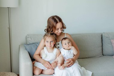 Genç mutlu anne ve kızları evin içinde. Anneler Günü. Samimi.