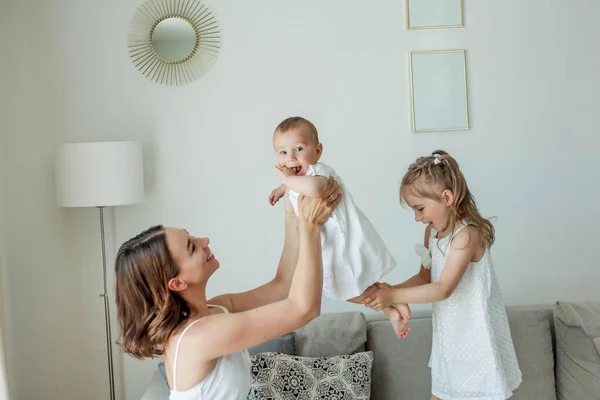 어린 어머니는 집안에서 딸들 과 함께 행복 한 모습을 하고 있습니다. 어머니들의 날. — 스톡 사진