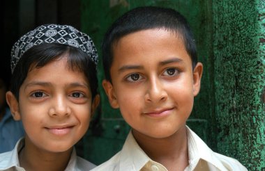Pakistan 'ın Hayber Pakhtunkhwa ilinde Peşaver. Peşaver, Pakistan 'da iki çocuğun portresi. Çocuklar gülümsüyor, yeşil bir kapı aralığında duruyorlar, yumuşak tenli ve parlak gözlü. Peşaver 'de iki oğlan..