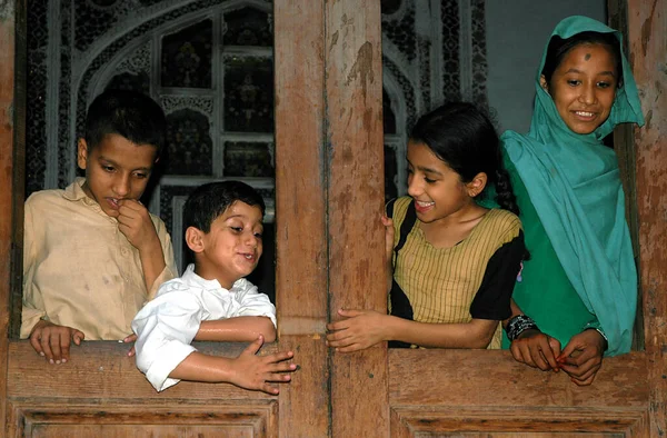 巴基斯坦开伯尔 普赫图赫瓦省的白沙瓦 在巴基斯坦白沙瓦的一个家 四个孩子从窗户往下看 白沙瓦一所老房子里的四个巴基斯坦小孩开心地微笑着 — 图库照片
