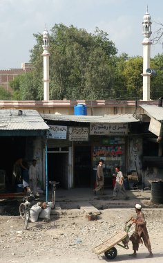 Afganistan, Nangarhar Eyaleti 'ndeki Jalalalabad. Afganistan, Celalabad 'da Müslüman Afgan halkı sokakta yürüyor. Biri eczanenin dışındaki toprak yolda bir arabayı itiyor. Celalabad, Afganistan