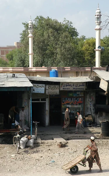 阿富汗楠格哈尔省贾拉拉巴德 阿富汗穆斯林人走在阿富汗贾拉拉巴德的一条街上 一个人在药店外面的土路上推着一辆购物车 阿富汗贾拉拉巴德 — 图库照片