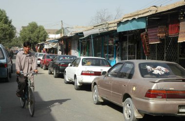 Afganistan 'da Kabil. Afganistan, Kabil 'de bir adam yol boyunca bisiklet sürüyor. Kabil Afganistan 'ın başkentidir. Yol, bisikletçi, erkek bisikleti, bisiklet, mağaza, araba, Kabil, Afganistan.
