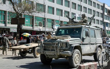 Afganistan 'da Kabil. Afganistan, Kabil 'de bir ISAF aracının çatısında makineli tüfek taşıyan bir asker var. Yerel halk hayata devam ediyor. Silah, asker, savaş, sokak, Kabil, Afganistan.